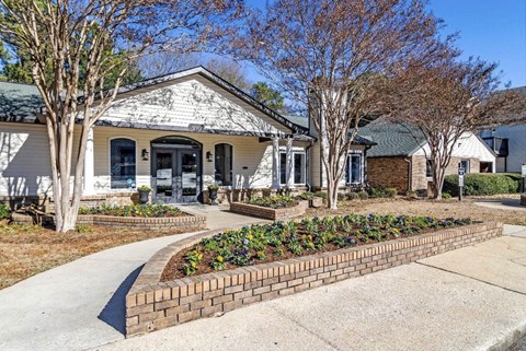 A white house with a brick flower bed in front at The Onyx Hoover Apartments, Hoover, AL, 35216